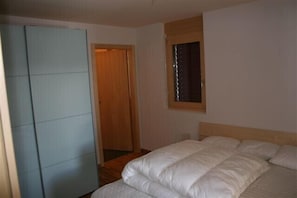 A bedroom with a bed, a wardrobe, and a window.