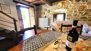 A rustic interior with a wooden table set for dining, a bottle of wine, and a stone wall.