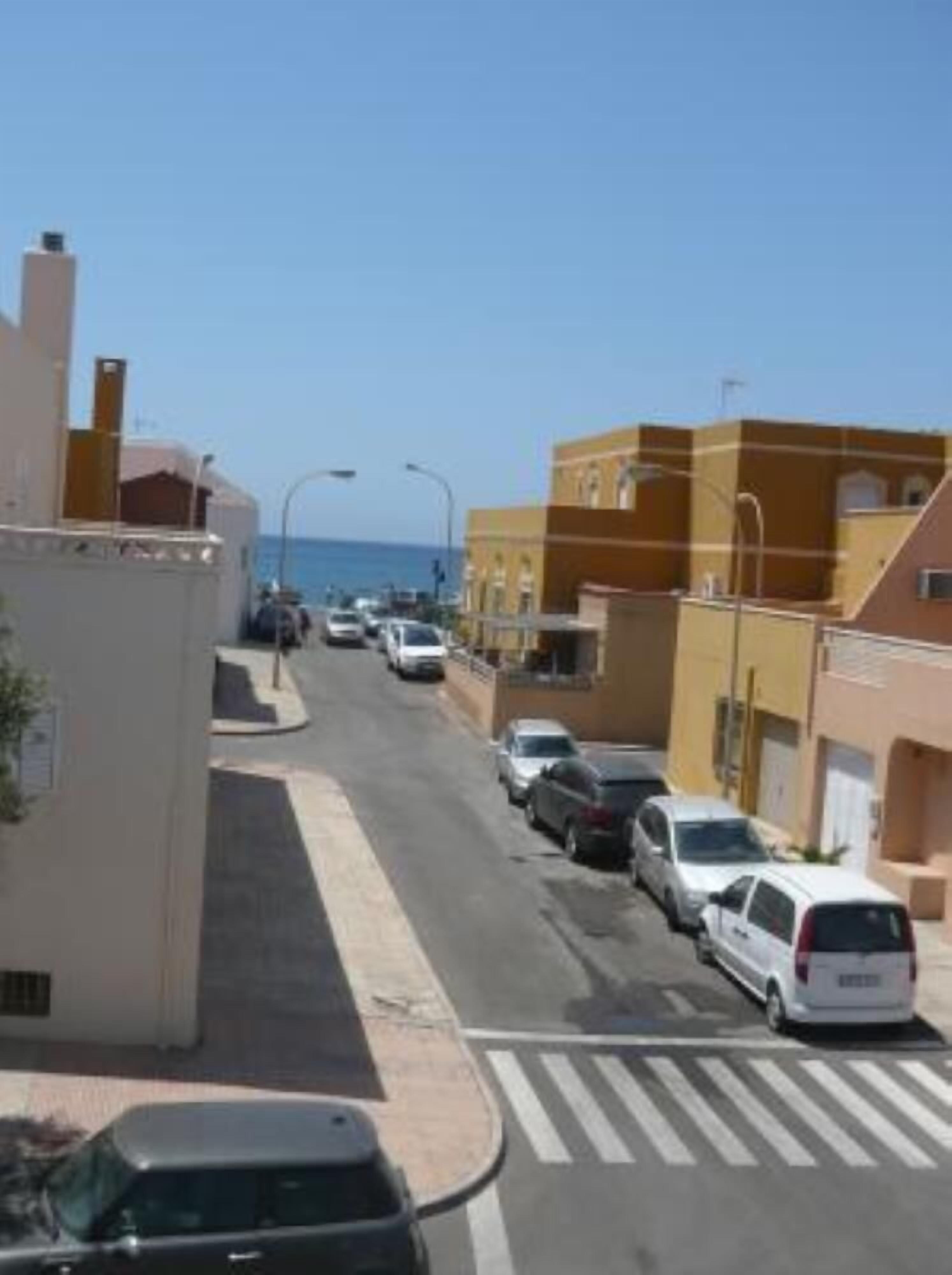 Vista de la calle con coches aparcados, edificios y cielo despejado.