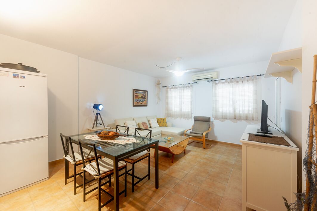 Un espacio habitable compacto con comedor, sofá, silla, televisor y refrigerador.