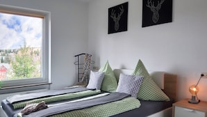 Une chambre à coucher avec un lit, des oreillers, une table de chevet, une lampe et des œuvres d’art accrochées au mur.