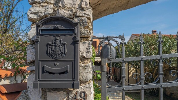 Ein Briefkasten mit Wappen und der Nummer 49 an einer Steinmauer.