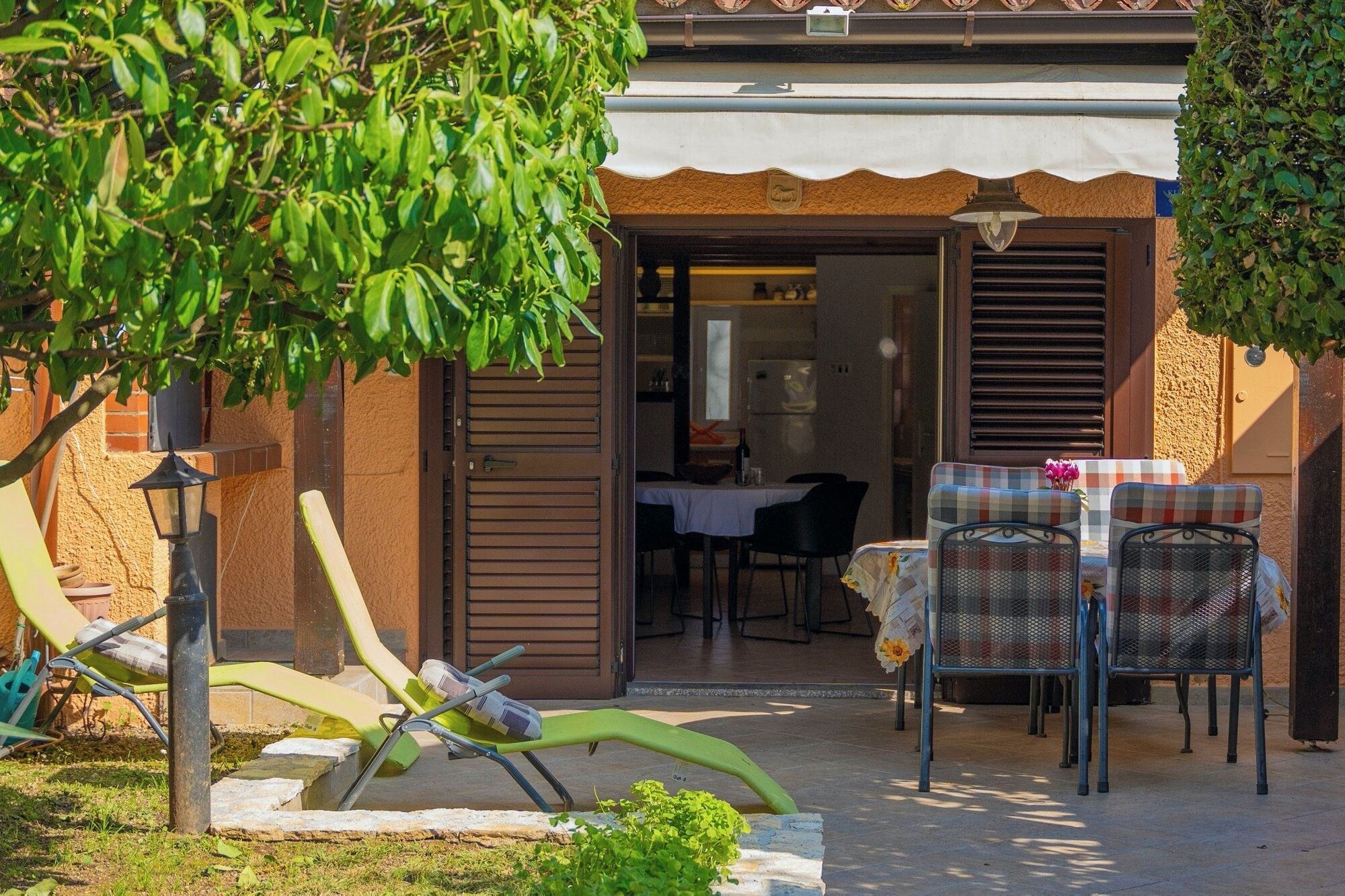 Een terras met buitenmeubilair, een tafel en uitzicht op het huis.