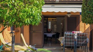 Eine Terrasse mit Sitzgelegenheiten im Freien, einem Tisch und Blick ins Haus.