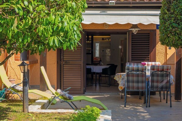 A patio area with outdoor seating, a table, and a view into the house.