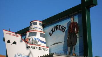 Een muurschildering van een schip genaamd 'MARKEN EXPRESS' met een persoon die op de boeg staat.