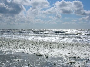 En strand med bølger og let overskyet himmel.