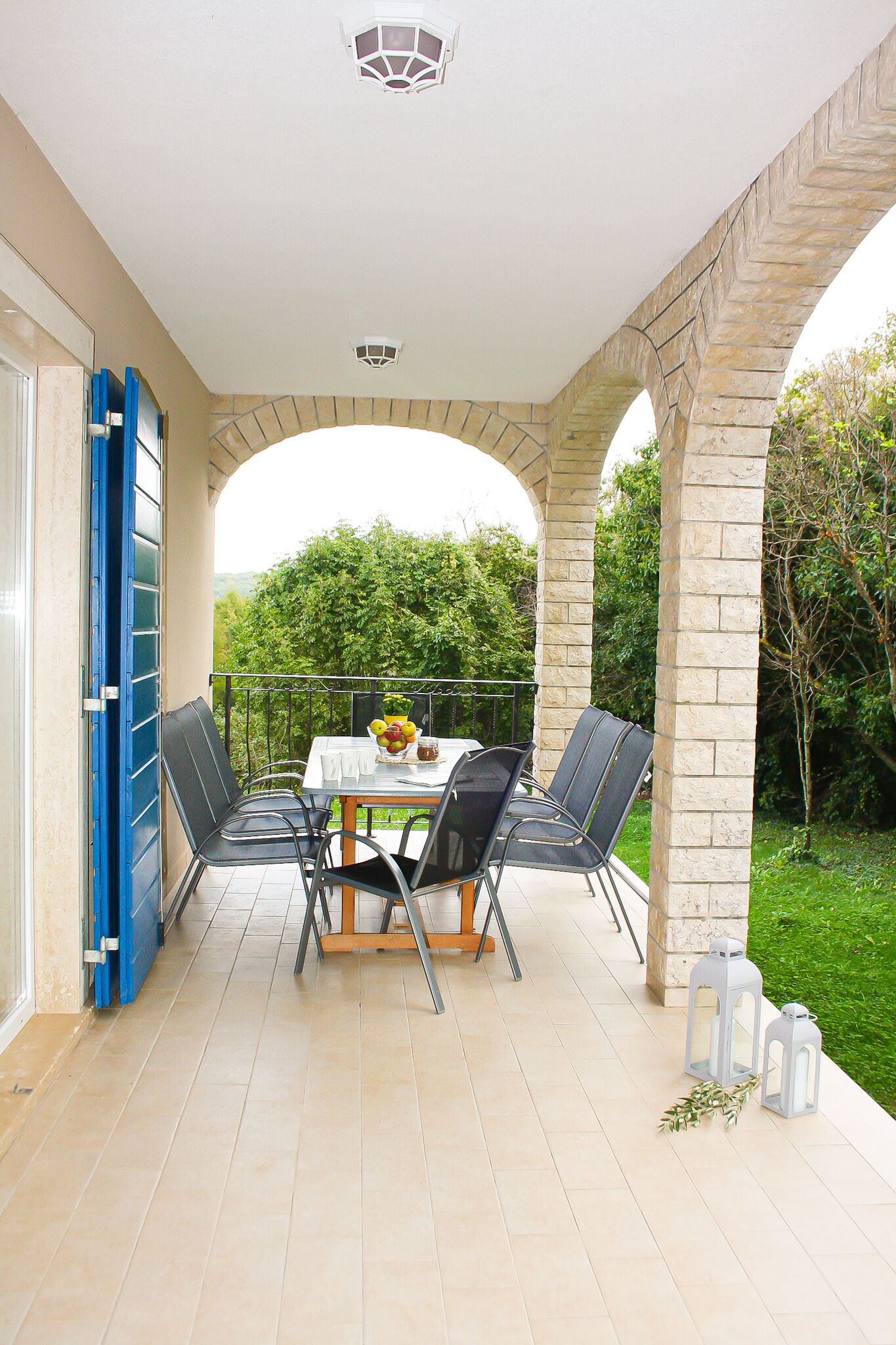 Une terrasse couverte avec une table et des chaises, une vue sur la verdure et des arches en pierre.