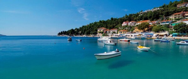 A coastal town with boats docked along the shore, buildings on a hillside, and a clear blue sea. - Luxury villa with pool in a small Istrian village near the sea (Labin)