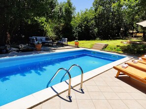 A rectangular swimming pool with clear blue water, surrounded by a tiled deck. There are two metal pool ladders on the deck, and a few lounge chairs with towels. - Luxury villa with pool in a small Istrian village near the sea (Labin)