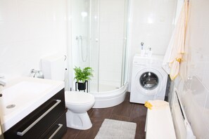 A modern bathroom with a glass-enclosed shower, a white toilet, a washing machine, and a sink. - Luxury villa with pool in a small Istrian village near the sea (Labin)