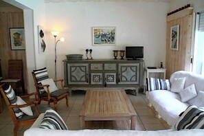 Een woonkamer met een bank, stoelen, een salontafel, een kast en een televisie.