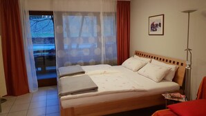 Une chambre d’hôtel avec un lit, une table de chevet, une lampe, une fenêtre avec des rideaux et une vue sur l’extérieur.