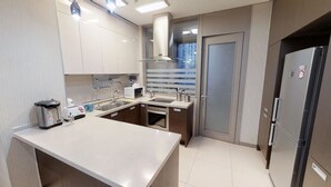Una cocina moderna con una isla central, electrodomésticos de acero inoxidable y vistas de la ciudad a través del ventanal.
