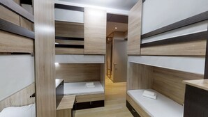 Una habitación moderna y compacta con almacenamiento integrado y una cama pequeña.