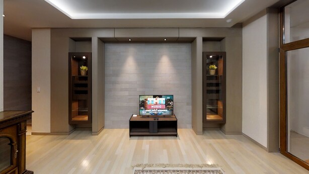 Una sala de estar moderna con un televisor de pantalla plana montado en la pared, estanterías de madera a cada lado y piso de madera.