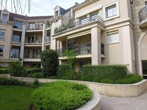 A multi-story residential building with balconies, a garden area with hedges, and a curved pathway. - Air-conditioned apt. 67 m2 air-conditioned, standing residence/town center, certified stars (Maisons-Laffitte)