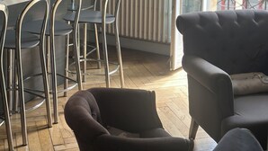 A dining area with a table and chairs, a radiator, and a window with a view of buildings. - STANDING APARTMENT IN THE CENTER OF LA ROCHELLE 2 STEPS FROM THE OLD PORT AND BEACH (La Rochelle)