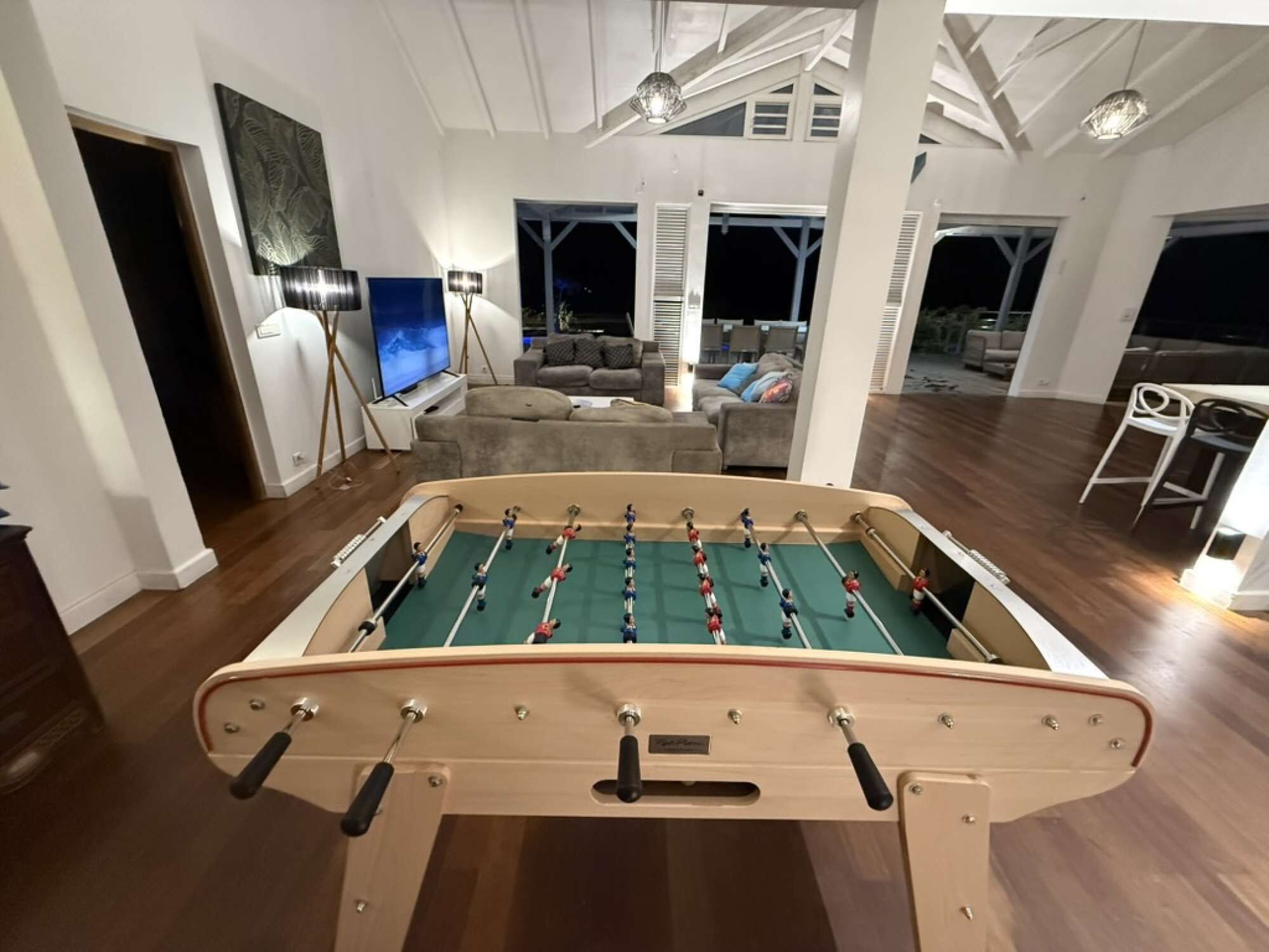 A spacious living area with a foosball table, a television, and a seating area with sofas and a coffee table.