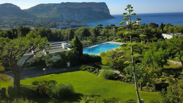 A pool surrounded by lush greenery and a view of the sea and mountains. - Cassis 62m2 + Balcony 10m2, Air Conditioning, Panoramic Sea View, Pool, Tennis (Cassis)