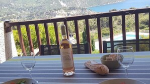 A table set for two with a bottle of wine, glasses, bread, and salad bowls, overlooking a mountainous landscape and a body of water. - Cassis 62m2 + Balcony 10m2, Air Conditioning, Panoramic Sea View, Pool, Tennis (Cassis)