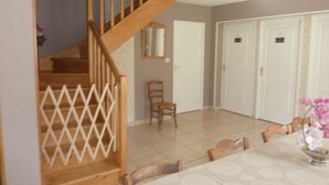 A dining area with a staircase, chairs, a table, and a door.