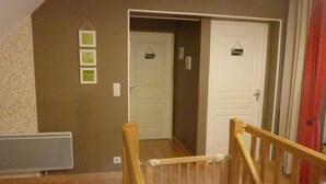 A room with a wooden staircase, a radiator, and two doors.