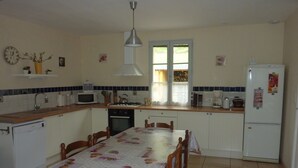 A compact kitchen with white cabinets, a microwave, a kettle, and a refrigerator.