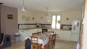 A compact kitchen with a dining table, chairs, a refrigerator, and a microwave.