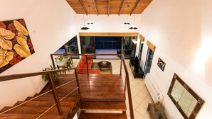 Una escalera de madera que conduce a una sala de estar con un sofá, una mesa de centro y vistas al exterior.