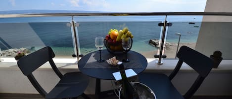 Un balcón con una mesa preparada para dos personas, que incluye un frutero, copas de vino y una botella de champán en un cubo.