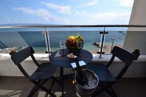 A balcony with a table set for two, featuring a fruit bowl, wine glasses, and a bottle of champagne in a bucket.