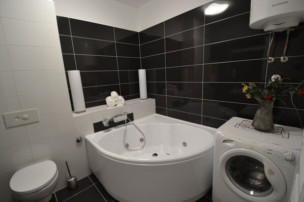 A modern bathroom with a bathtub, toilet, and washing machine.