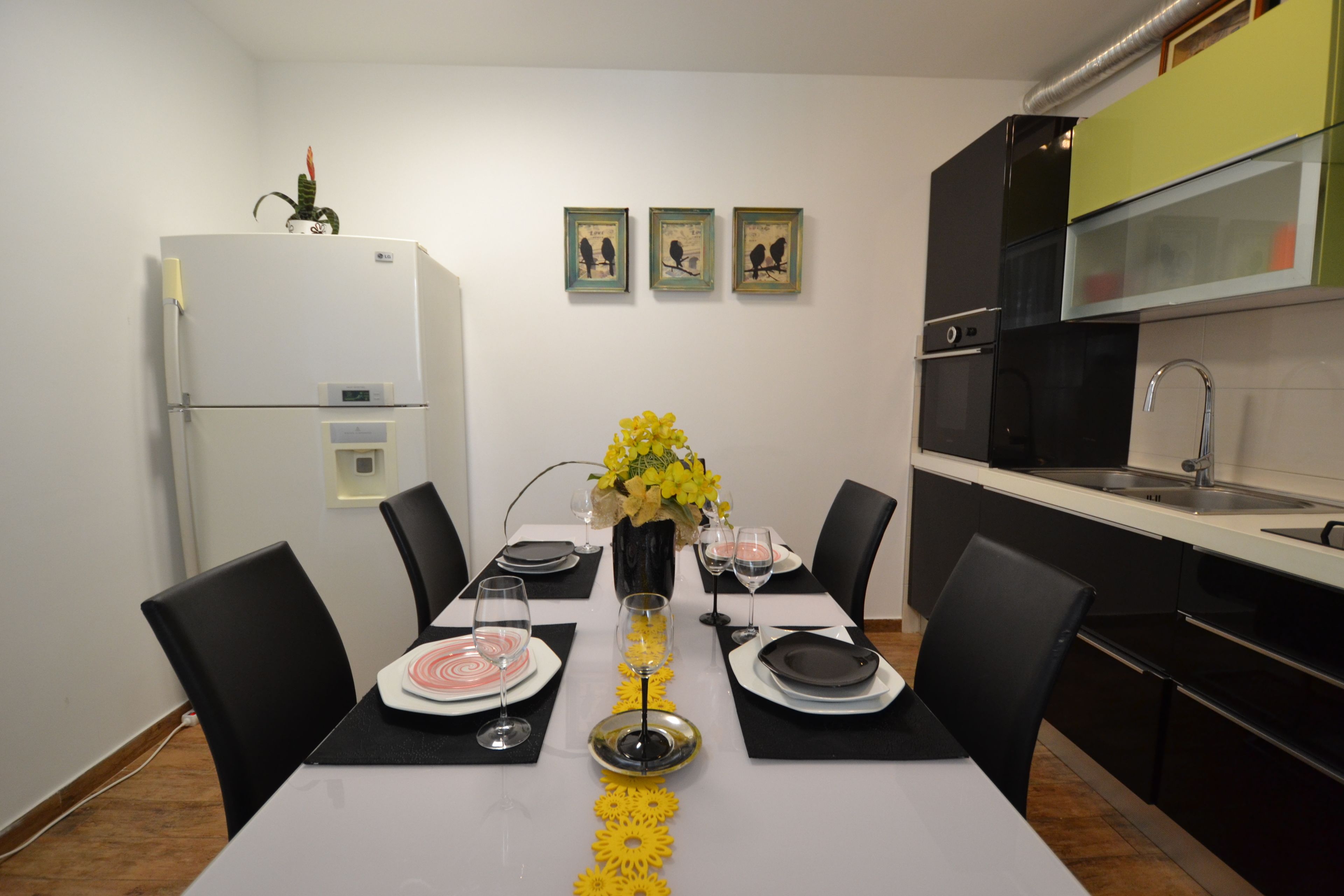 Een eettafel gedekt met borden, glazen en een bloevas.