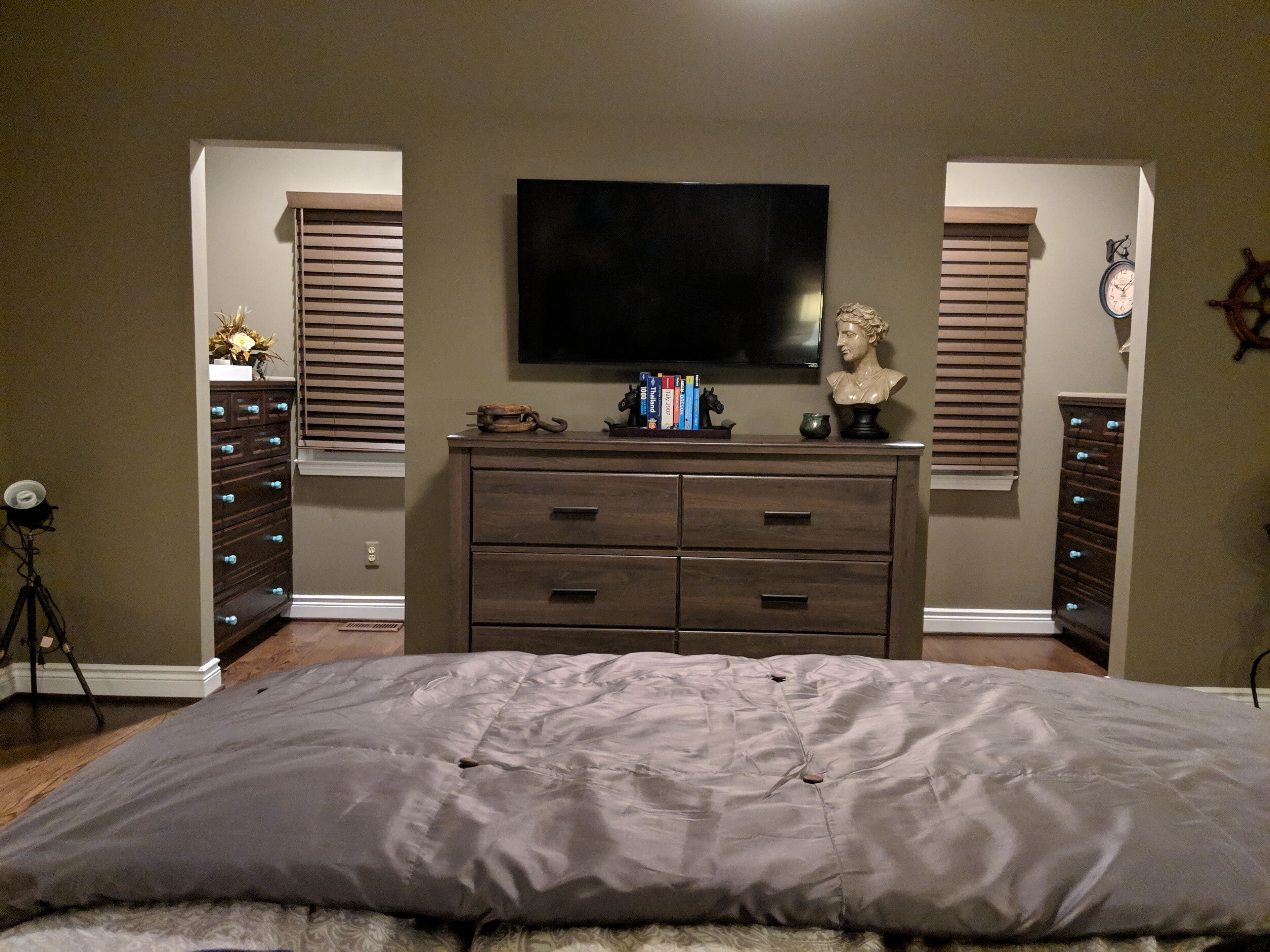 Une chambre à coucher avec un lit, une commode, un téléviseur et une horloge au mur.