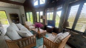 Una sala de estar acogedora con muebles de mimbre, un televisor y una estantería.
