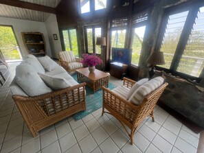 A cozy living room with wicker furniture, a television, and a bookshelf.