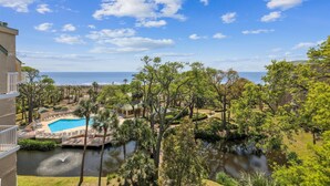 Un resort con piscina, una fuente pequeña y vista al océano.