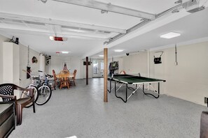 A spacious indoor area with a ping pong table, bicycles, and a table with chairs.