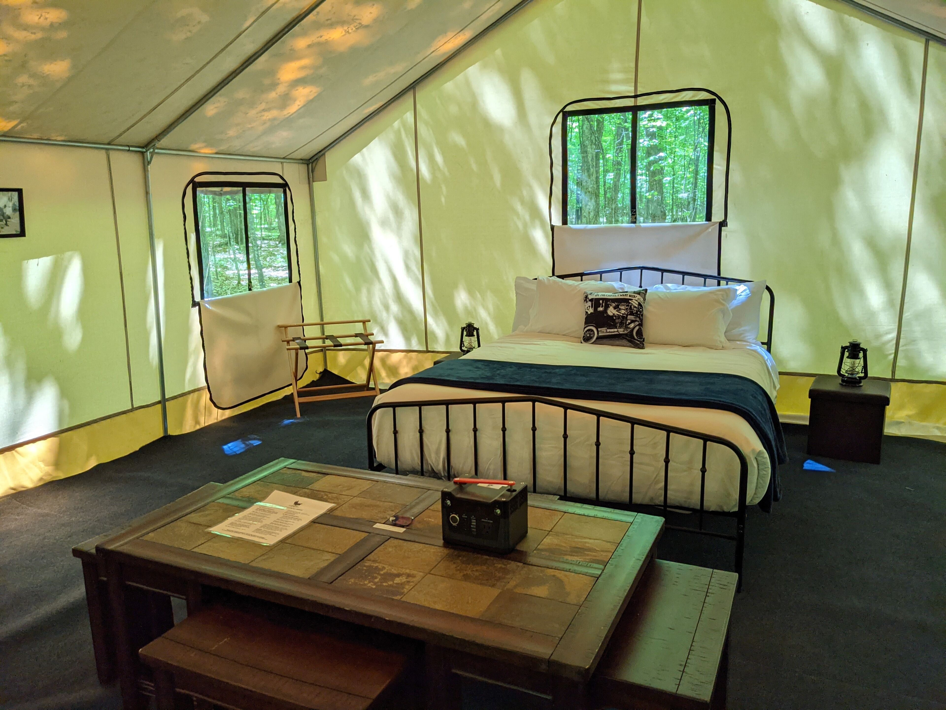 Una habitación con carpa, una cama, una mesa y un banco.