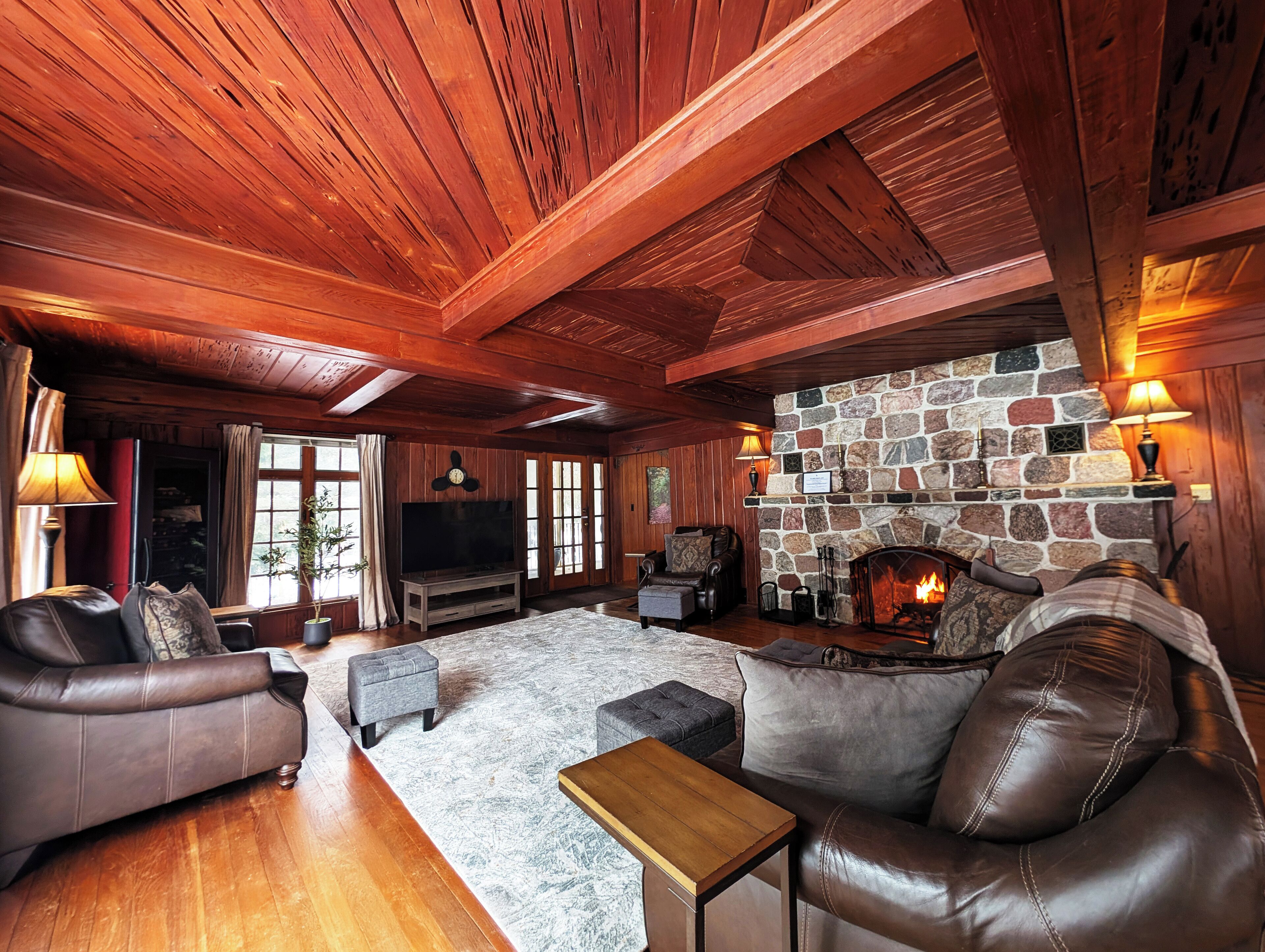 A cozy living room with a stone fireplace, leather sofas, and a flat-screen TV.