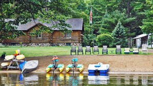 A log cabin with a dock, kayaks, and lounge chairs by a lake. - POV Lake Resort & Glamping Campground (Phelps)