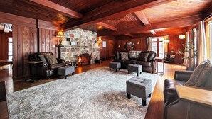 A log cabin interior with a stone fireplace, leather furniture, and wooden beams. - POV Lake Resort & Glamping Campground (Phelps)