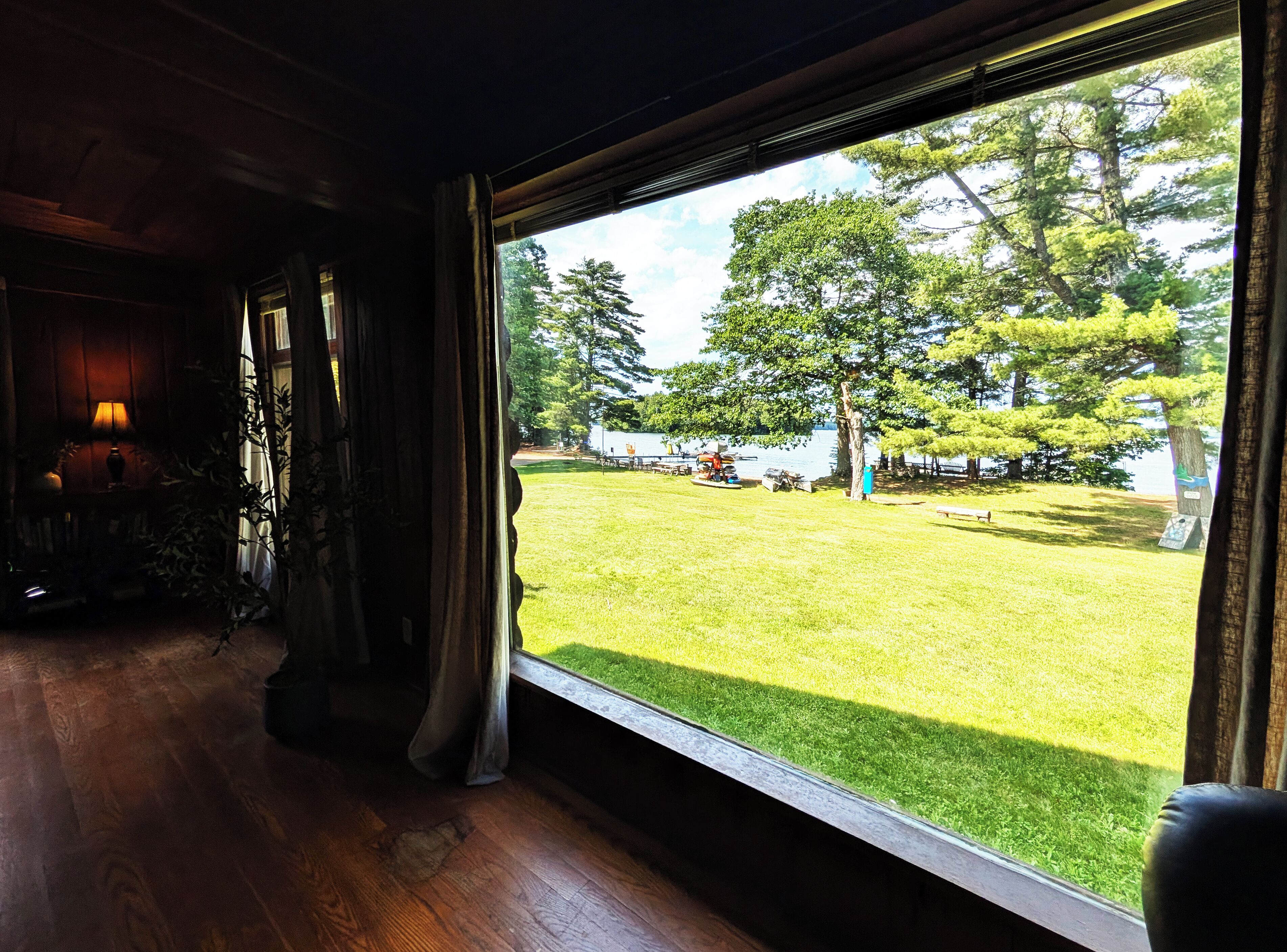A room with a large window overlooking a grassy outdoor area with trees and a lake.