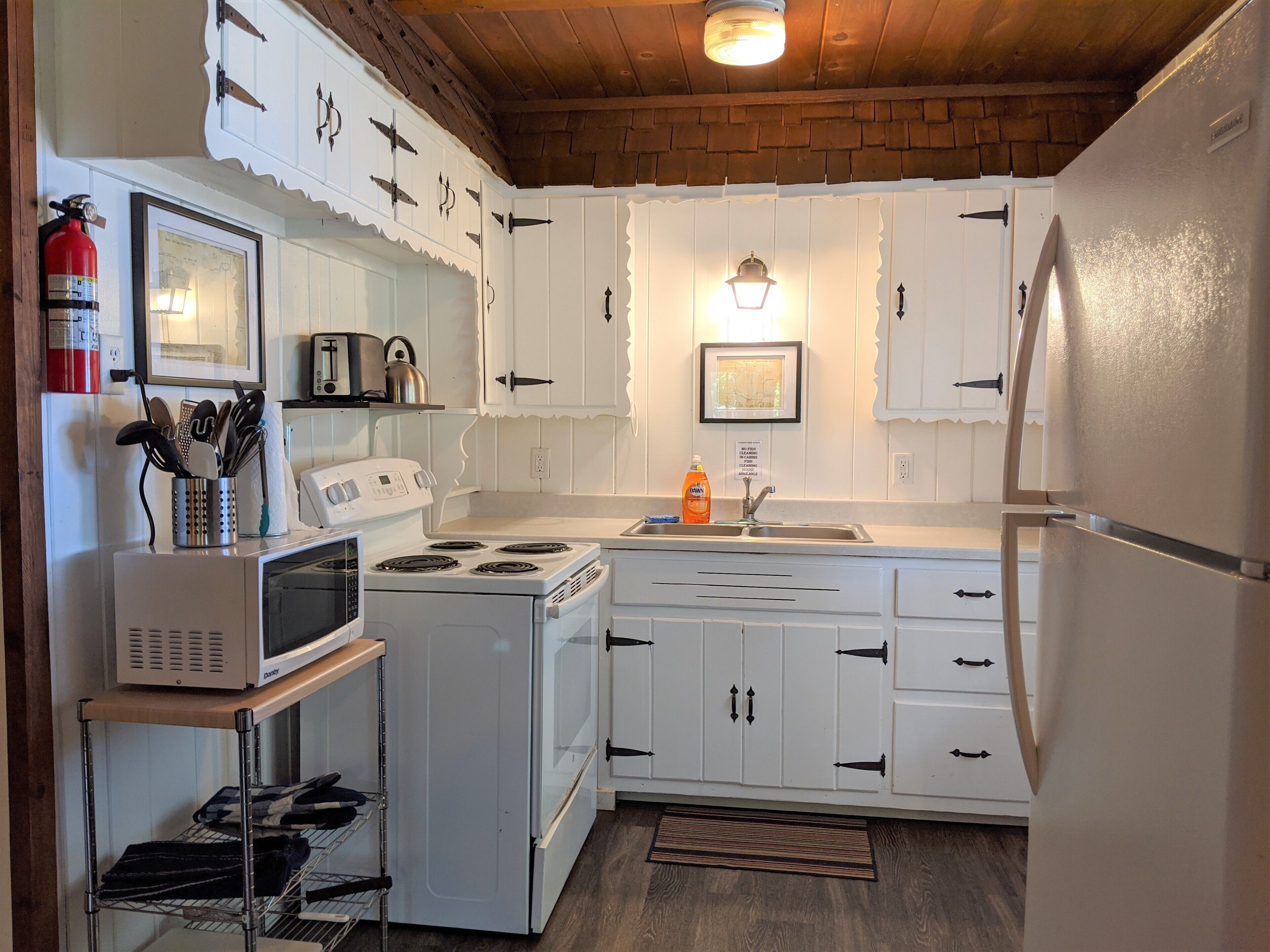 A kitchen with white cabinets, a stove, a microwave, and a refrigerator.