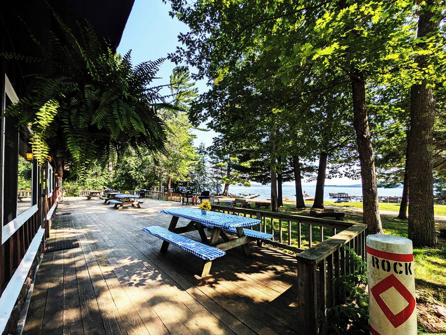 A wooden deck with picnic tables and benches, overlooking a body of water.