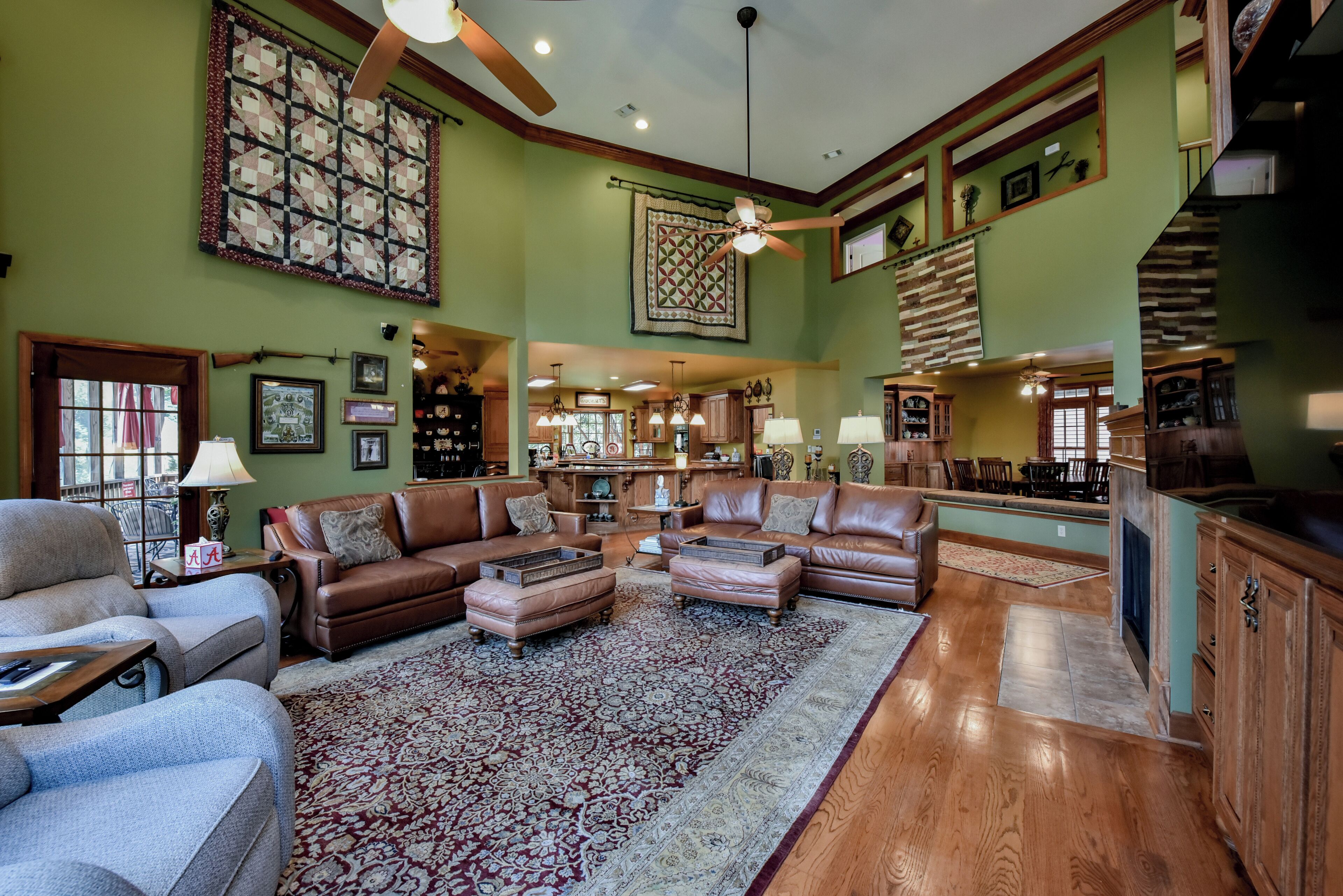 A spacious living room with leather sofas, a large rug, and a high ceiling with exposed beams.
