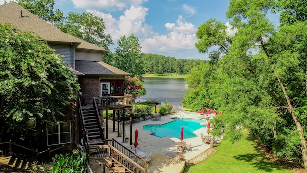 Una casa con piscina, terraza y vistas a un lago.