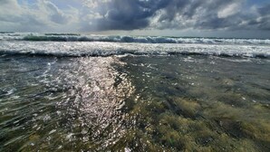A beach with waves and sunlight reflecting on the water.