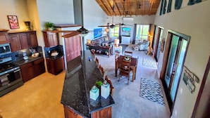 A spacious kitchen with a central island, wooden ceiling beams, and a dining area with a sofa and chairs.